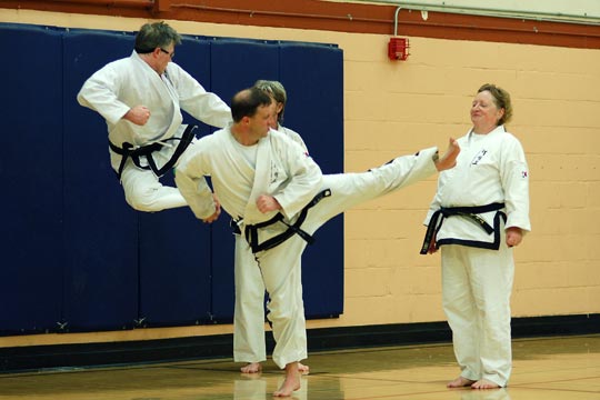 Black belts practice kicks during partner drills at an All-School workout.