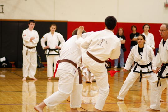 Two brown belt men spar at a tournament.