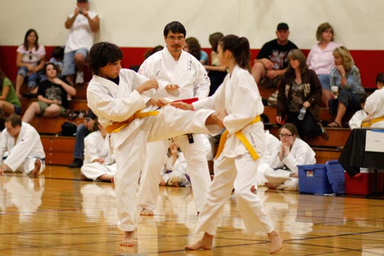 A yellow belt boy and girl spar at a tournament.
