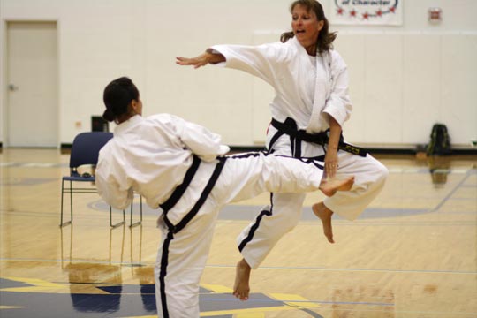 Two black belt women spar.