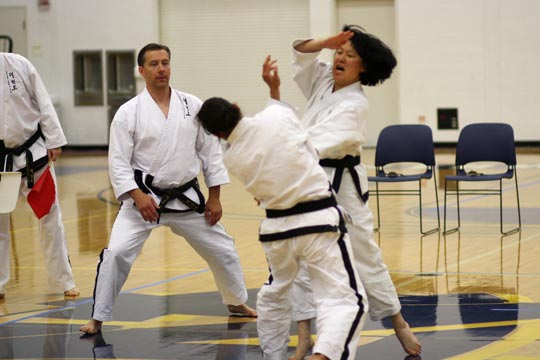 Two black belt women spar at a tournament.