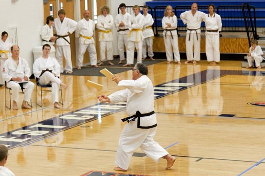 A black belt breaks a self-suspended board with an inward knifehand.