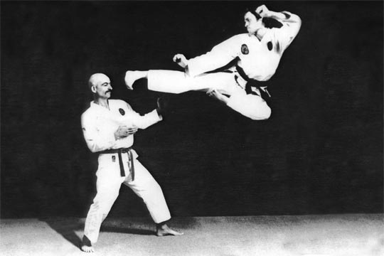 Mr. Bailey doing a jumping side kick toward a standing opponent.
