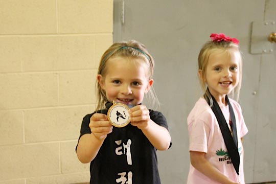 Two children show the medals that they earned at a tournament.