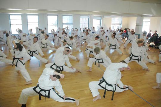 A room full of students stretch on a wood floor.