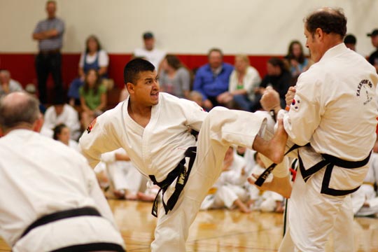 Two black belt men spar at a tournament.